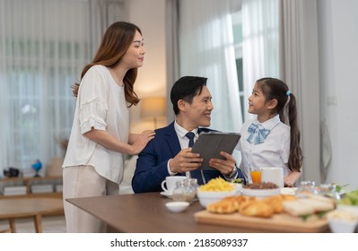 In The Morning At Home The Family Husband Hold Tablet Read News Wife And Children Girl Happy Smile Talking To Each Other And Laughting Before Breakfast And Go To Work And School
