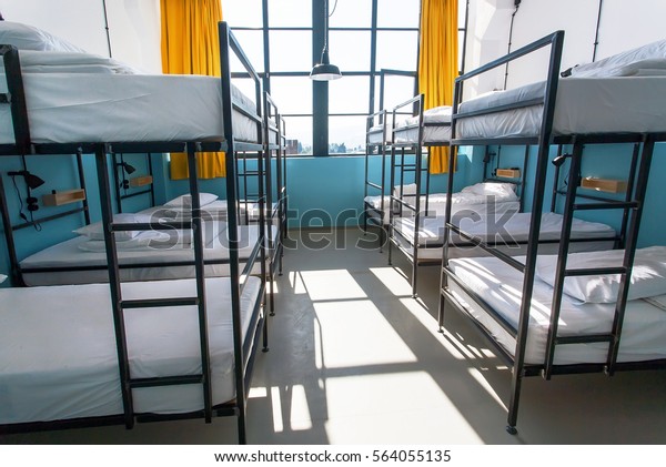 Morning inside the hostel bedroom\
with clean white beds for students and lonely young\
tourists
