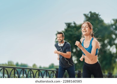 Morning jogging. Image of happy excited smiling young couple, runners running together, woman train with man, or bearded fit coach exercising outdoors. Fitness, sport city marathon workout concept. - Powered by Shutterstock