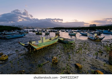 Morning landscape of stranded boats on Tamsui river during a low tide, at Bali District, New Taipei City, Taiwan. Beautiful sunrise of Tamsui river with Datun Mountain on distant horizon in background - Powered by Shutterstock