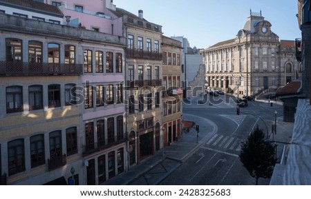 Morning light washes over a European cityscape, where historic buildings line the street leading to an ornate stone edifice, capturing a blend of daily life and architectural heritage.