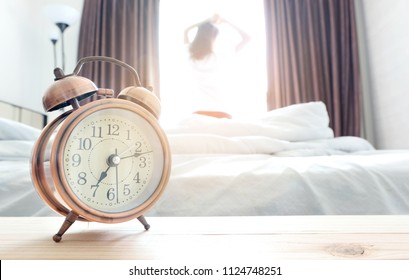 Morning of a new day, alarm clock wake up woman sitting in the room. A woman stretch the muscles at window. Health and care concepts - Shutterstock ID 1124748251