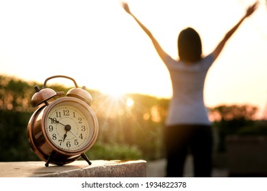 Morning of a new day, alarm clock wake up woman sitting in the room. A woman stretch the muscles at window. Health and care concepts.soft focus
