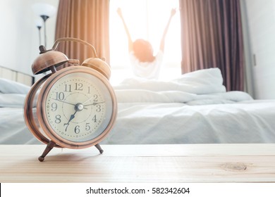 Morning Of A New Day, Alarm Clock Wake Up Woman In The Room. A Woman Stretch The Muscles At Window. Health Concept.