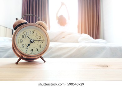 Morning of a new day, alarm clock wake up woman sit in the room. A woman stretch the muscles at window. Health concept. - Shutterstock ID 590543729