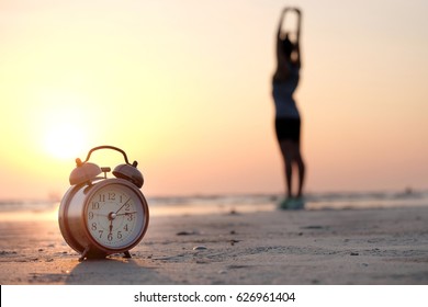 Morning Of A New Day, Alarm Clock Woman Playing Yoga And Stretching Muscles On The Beach Sunlight In Morning.