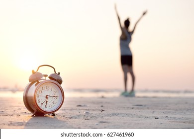 Morning Of A New Day, Alarm Clock  Woman Playing Yoga And Stretching Muscles On The Beach Sunlight In Morning. Health Concept.