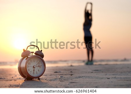 Morning of a new day, alarm clock woman playing yoga and stretching muscles on the beach sunlight in morning.