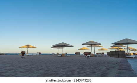 Morning On The Red Sea Coast. The Sun Illuminates The Umbrellas. Sunbeds And Ceramic Urns Stand In The Shade On The Sand. Clear Blue Sky. Egypt. Safaga
Morning On The Red Sea Coast. The Sun Illuminate