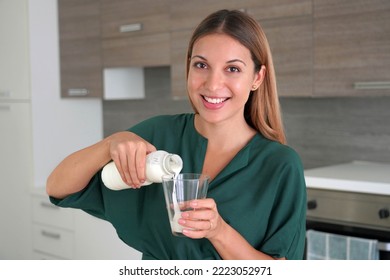Morning Portrait Of Beautiful Smiling Woman Filling The Glass With Kefir. Looks At Camera.