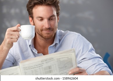 Morning portrait of handsome guy reading newspaper and holding coffee cup. - Powered by Shutterstock