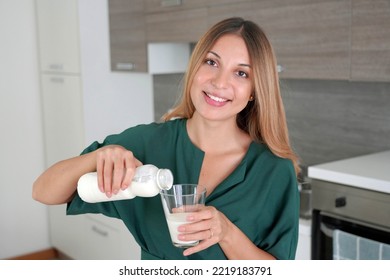 Morning Portrait Of Young Smiling Woman Fills The Glass With Kefir. Beautiful Girl Drinking Milk. Looks At Camera.