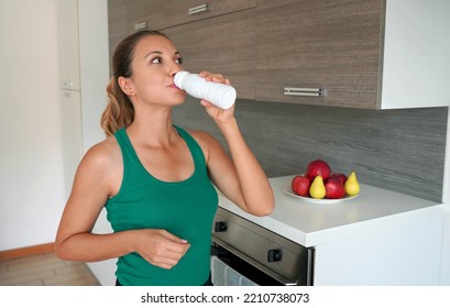 Morning Portrait Of Young Woman Drinking Whey Protein Beverage. Home Fitness Girl Drinks Kefir From Bottle.