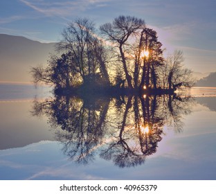 Morning reflection of trees on a small island in lake Annecy France.