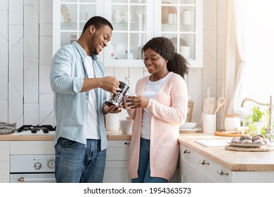 Morning Routine. Happy Young Black Couple Drinking Coffee In Kitchen Interior, Caring African American Husband Holding French Press And Pouring Caffeine Drink To Wife's Cup, Free Space - Powered by Shutterstock