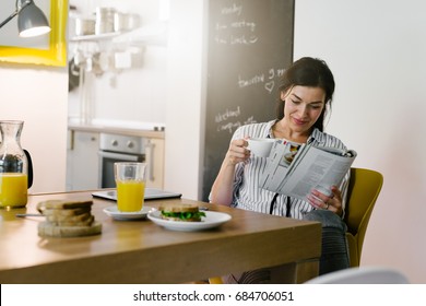 Morning Routine. Woman Reading Newspaper During Breakfast At Her Home