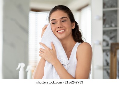 Morning Skincare Routine. Happy Female Drying Face With Soft Towel Standing In Modern Bathroom Indoor. Beauty Care And Facial Skin Care Cosmetics, Wellness And Pampering Concept