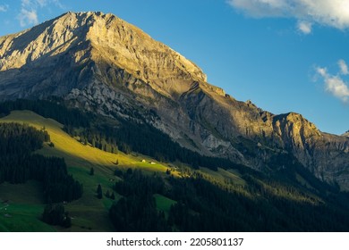 the morning sun illuminate the clouds and the peaks of Swiss mountains around Adelboden. first light in the valley from Boden, under the high mountain big wager, with green meadows, forests and rocks - Shutterstock ID 2205801137