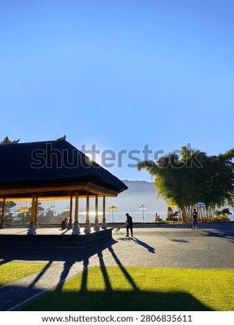 Morning sunlight casting long shadow of a man and the building at the courtyard of Ulun Danu Beratan Temple in Bedugul, Bali