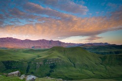 Morning Sunlight Reflects Beautiful Hues Of Orange On Clouds Above The Famous Drakensberg Mountain Range.