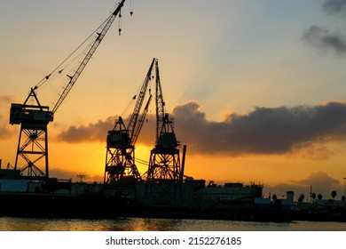 Morning Sunrise Off The Coast Of Long Beach, California, With Cranes Silhouetted By The Sun 