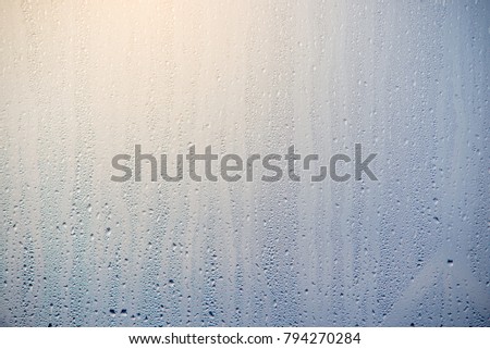 The morning sunrise through the raindrops on the glass. Condensation on Windows in winter. The texture of the water abstraction