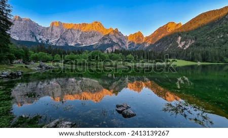 Morning sunrise view of Superior Fusine Lake (Laghi di Fusine) with majestic Mount Mangart in background in Tarvisio, Friuli Venezia Giulia, Italy. Captivating Water Reflection in tranquil atmosphere