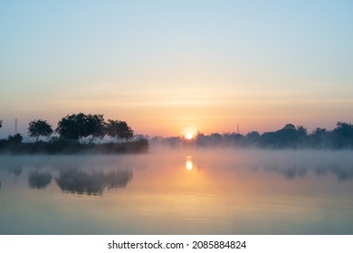 Morning Time On The Lake And Mist Fog.The Trees And Foggy With Sun Rise Sky And Reflective In The Water.Natural Landscape In The Morning Time.