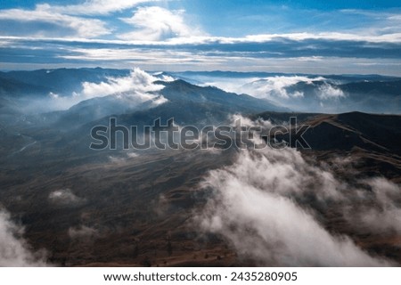 Morning view with mountain village and fog an clouds in Romania