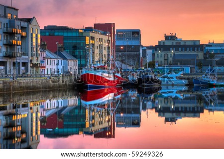 morning view on row of buildings and fishing boats in Galway Dock with sky reflected in the water, HDR image