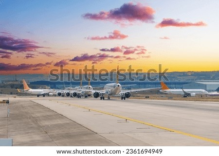 Morning view of a queue of planes ready for takeoff taxiing on the runway, against the backdrop of a beautiful sky at dawn sunrise