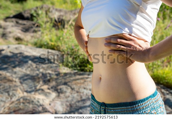 Morning view of young beautiful woman doing yoga\
outdoor. Close-up view of the stomach of a young yogi girl. Young\
slim woman is doing breathing exercises. Outdoor sports training.\
Press muscle.