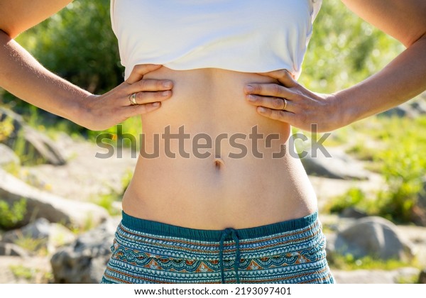 Morning view of young beautiful woman doing yoga\
outdoor. Close-up view of the stomach of a young yogi girl. Young\
slim woman is doing breathing exercises. Outdoor sports training.\
Press muscle.
