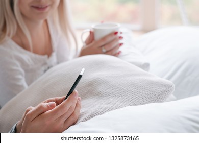 Morning Wake Up Ritual. Young Couple In Bed With Drink And Smartphone.