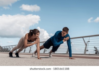 Morning Workout Concept. Happy Adult Athlete Woman And Man Doing Shoulder Tap Exercise, Standing In Plank Pose, Making Sport Training Outdoors Together