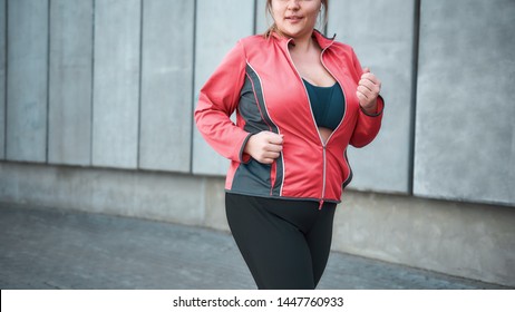 Morning workout. Young plus size woman in sport clothes running outdoors. Healthy lifestyle. Weight losing