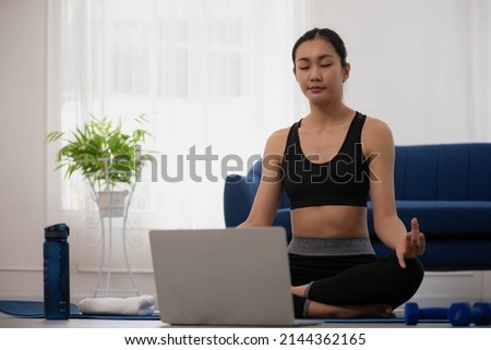 Morning yoga with an Asian woman, sitting in Easy position, Sukhasana posture, and meditating online.
