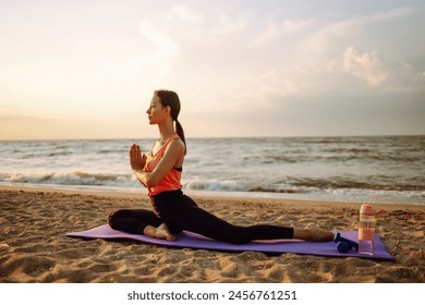 Morning yoga. Young beautiful woman doing exercises on beach at sunrise. Calmness and balance, a healthy lifestyle. - Powered by Shutterstock