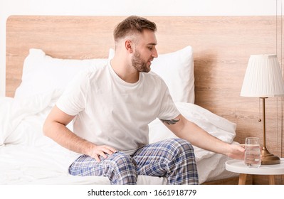 Morning Of Young Man  Taking Glass Of Water From Bedside Table