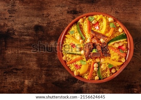 Moroccan couscous with meat, traditional festive dinner, shot from above on a wooden background with copy space