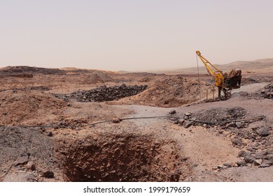 Moroccan Industrial Working Construction With Yellow Hydraulic Excavator Machine Crane At Coal Mine Soil Ground Site At Sand Dunes In Hot African Sahara Desert Near Oriental Merzouga, Morocco, Africa.