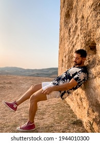 Morocco - August 25, 2020; Calm Caucasian Man Taking His Time To Relax And Pose Carelessly Direct To The Sun In Morocco Wearing Red Converse Shoes And Putting His Right Leg Up