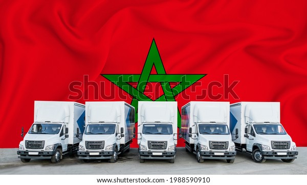 Morocco flag in the background. Five\
new white trucks are parked in the parking lot. Truck, transport,\
freight transport. Freight and logistics\
concept