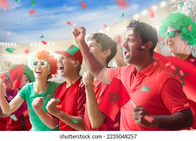 Morocco football supporter on stadium. Moroccan fans on soccer pitch watching team play. Group of supporters with flag and national jersey cheering for Morocco. Championship game. - Shutterstock ID 2235048257