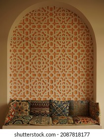 Morocco interior style. Colorful asian pillows on the couch near wall with pattern. Middle east arch interior. Arabic style. Morocco design room