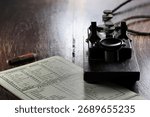 morse key with morse code chart on desk