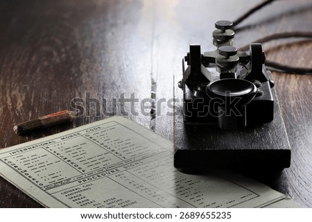 morse key with morse code chart on desk