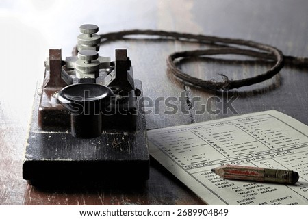 morse key with morse code chart on desk