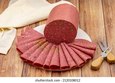 Mortadella salami on a wooden background. Salami with pistachio and black pepper.