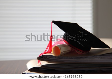 mortar board on stack of files